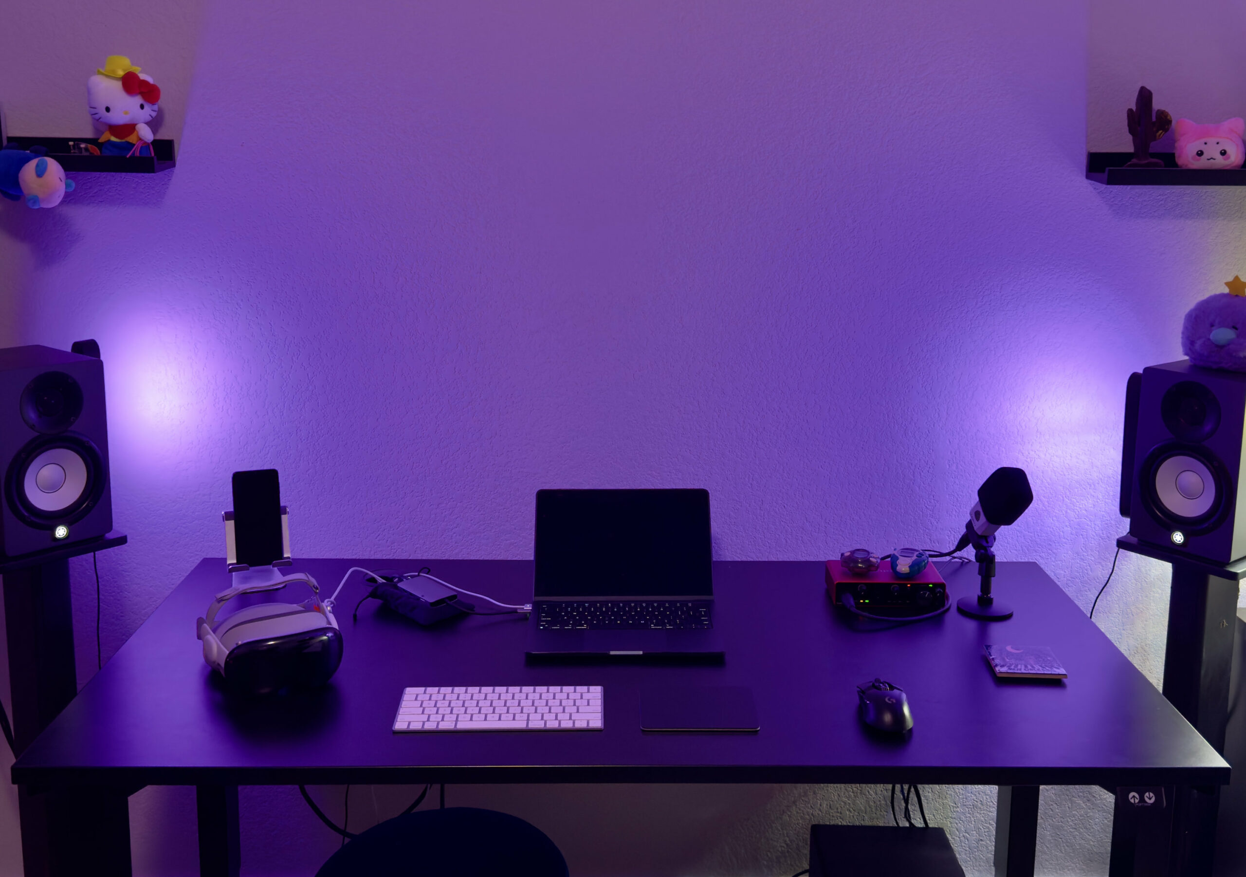 A black desk with a Vision Pro, macbook air, mouse and trackpad, and an audio interface. There are two speakers on each side of the desk facing me.